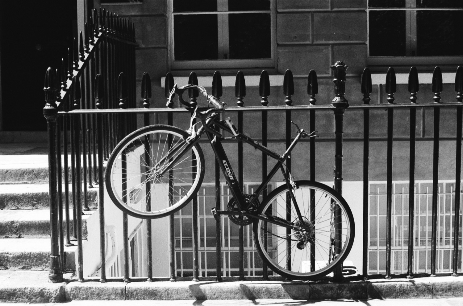 Bicycle against iron railings, black and white
