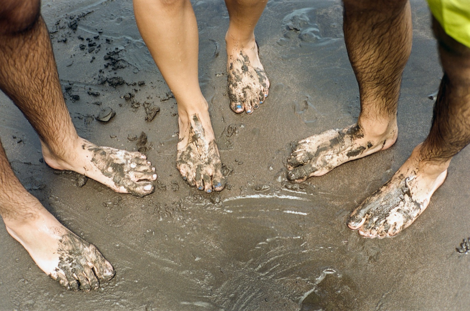 Muddy feet on black sand beach